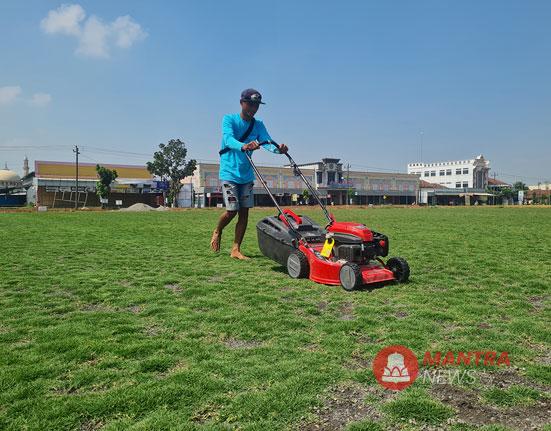Seorang pekerja tengah memotong rumput lapangan