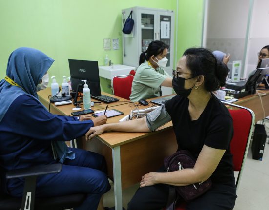 Seorang petugas kesehatan sedang memeriksa pasien. Seluruh masyarakat Indonesia berhak merasakan prograam UHC yang didanai APBD.