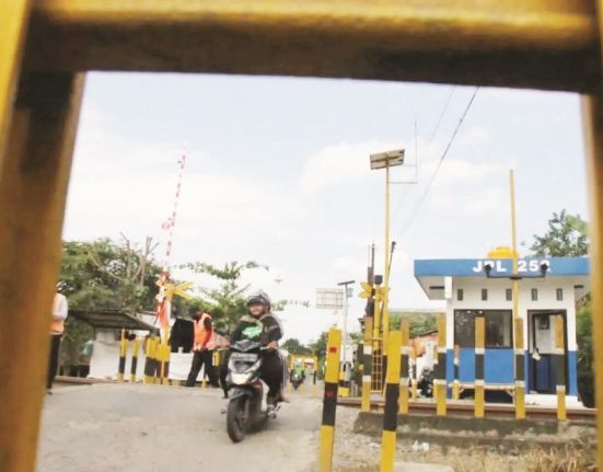 Petugas berjaga mengatur lalu lintas sementara pengendara melintasi jalur perlintasan langsung di Desa Ketanon, Tulungagung, Minggu (16/2). (ant | Mantranews.id)