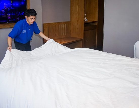 Seorang pekerja di hotel sedang merapikan seprei tempat tidur usai tamunya check-out. (Anta | Mantranews.id)