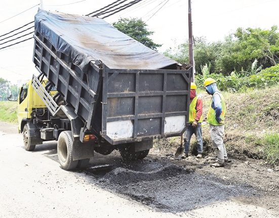 Sejumlah pekerja sedang memantau truk yang menurunkan material untuk penambalan jalan di salah satu ruas jalan di Kabupaten Kendal, Selasa (18/3). (Arvian Maulana | Mantranews.id) 