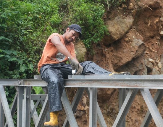 Seorang pekerja sedang fokus memasang kerangka pada Jembatan Bailey di Desa Tembelan, Kecamatan Petungkriyono, Kabupaten Pekalongan, Selasa (11/3). (Fahri Akbar | Mantranews.id)