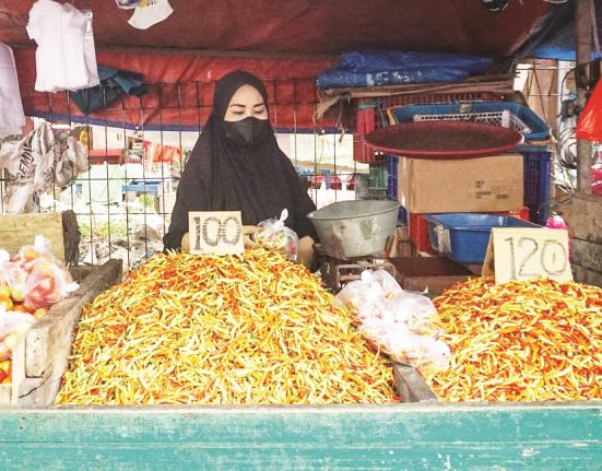 Seorang pedagang sedang menimbang cabai pesanan pembelinya. (Anta | Mantranews.id)