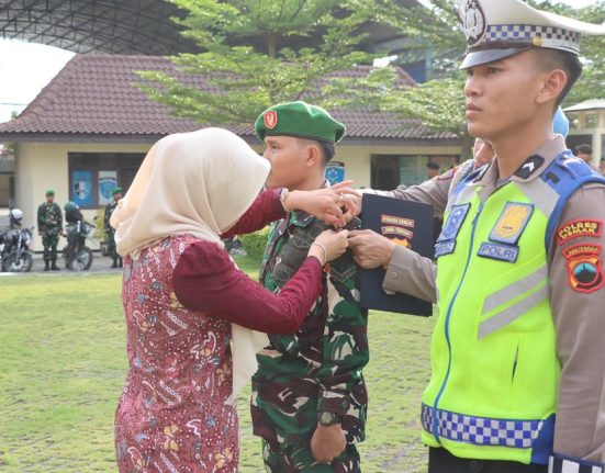 Bupati Demak Eisti’anah secara simbolis sedang menyematkan pita pada personel yang akan bertugas pada Operasi Ketupat Candi 2025 di lapangan Polres Demak, baru-baru ini. (M. Burhan | Mantranews.id)