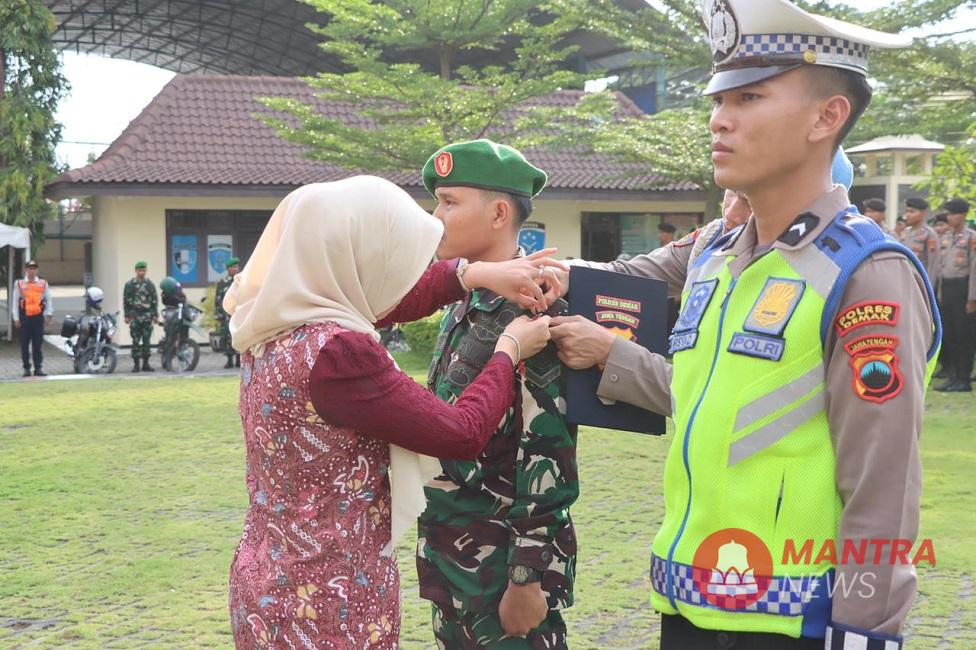 Bupati Demak Eisti’anah secara simbolis sedang menyematkan pita pada personel yang akan bertugas pada Operasi Ketupat Candi 2025 di lapangan Polres Demak, baru-baru ini. (M. Burhan | Mantranews.id)