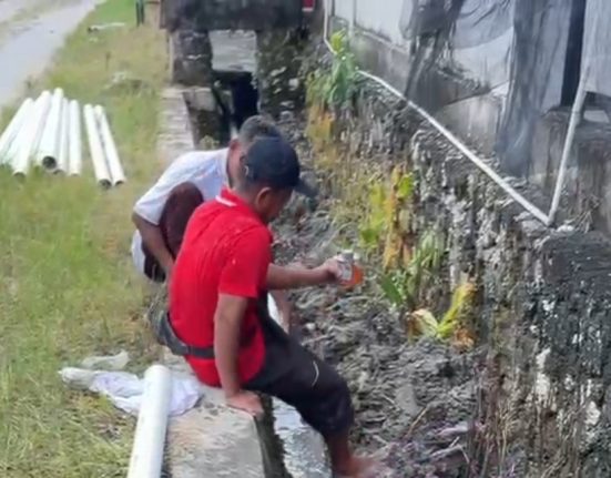 Dua orang pekerja hendak memasang paralon pembuangan limbah pemotongan ayam di Desa Pengkol, Penawangan, Kabupaten Gronogan. (Ahmad Abror | Mantranews.id) Aktivitas Pemotongan Ayam di Pengkol Grobogan Timbulkan Bau Busuk GROBOGAN, Mantranews.id – Warga Desa Pengkol, Kecamatan Penawangan, Kabupaten Grobogan mengeluhkan aktivitas pemotongan ayam di sekitar pemukiman yang menimbulkan bau busuk dan limbah cair. Kondisi tersebut dinilai mengganggu kenyamanan dan kesehatan lingkungan. Salah satu warga terdampak, Rika Melani, menyebutkan bahwa aktivitas pemotongan ayam dilakukan tanpa izin warga dan menghasilkan pencemaran lingkungan yang serius. "Permasalahan yang saya alami adalah pencemaran lingkungan. Usaha pemotongan ayam itu menghasilkan bau yang sangat menyengat dan limbah cair yang mengganggu kenyamanan warga," kata Rika saat dimintai keterangan, Jumat (18/4/2025). Menurutnya, terdapat lima kandang ayam dan lima lokasi pemotongan ayam di sekitar rumahnya yang tidak mendapat persetujuan dari warga. "Masing-masing ada lima, jadi 10 orang ya pemiliknya. Yang jadi masalah, ada pemotongan ayam yang limbahnya dialirkan ke perumahan warga, sehingga membuat bau yang tidak sedap dan sarang nyamuk," bebernya. Rika menambahkan, pengelolaan limbah yang buruk menyebabkan pencemaran air dan berpotensi menimbulkan penyakit. Selain bau menyengat, aktivitas tersebut juga mengakibatkan banyak lalat masuk ke dalam rumah warga. "Aktivitas tersebut di lingkungan padat tanpa izin warga sekitar dan menimbulkan efek lalat banyak di dalam rumah," imbuhnya. Masalah ini juga sempat memicu perselisihan antara Rika dan pemilik usaha. Ia berharap Dinas Lingkungan Hidup (DLH) Grobogan segera turun tangan untuk menangani masalah tersebut. "Kami harap DLH menindaklanjuti laporan ini dan melakukan langkah-langkah yang diperlukan untuk menjaga kenyamanan dan keselamatan lingkungan warga," harap Rika. Menanggapi hal tersebut, Kabid Penataan dan Peningkatan Kapasitas DLH Grobogan, Gunawan Widiyanto, membenarkan telah menerima laporan dari warga. "Betul, sudah ada laporan disampaikan ke kami. Nanti saya kabari untuk tindaklanjutnya," kata Gunawan. (Ahmad Abror | Mantranews.id)