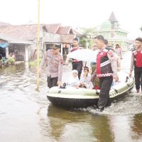 Sejumlah personel Samapta Polres Demak sedang mengantar siswa berangkat sekolah dengan menaiki perahu karet yang telah disiapkan, Senin (26/5/2025). (M. Burhan | Mantranews.id)