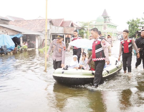 Sejumlah personel Samapta Polres Demak sedang mengantar siswa berangkat sekolah dengan menaiki perahu karet yang telah disiapkan, Senin (26/5/2025). (M. Burhan | Mantranews.id)