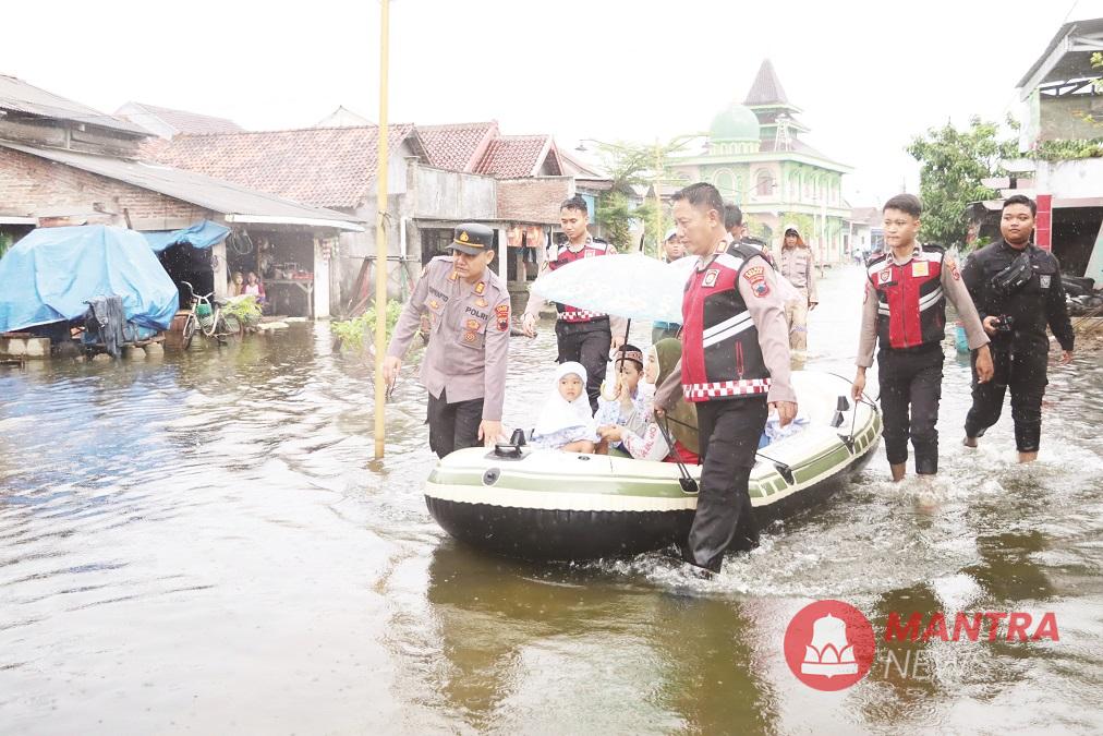 Sejumlah personel Samapta Polres Demak sedang mengantar siswa berangkat sekolah dengan menaiki perahu karet yang telah disiapkan, Senin (26/5/2025). (M. Burhan | Mantranews.id)