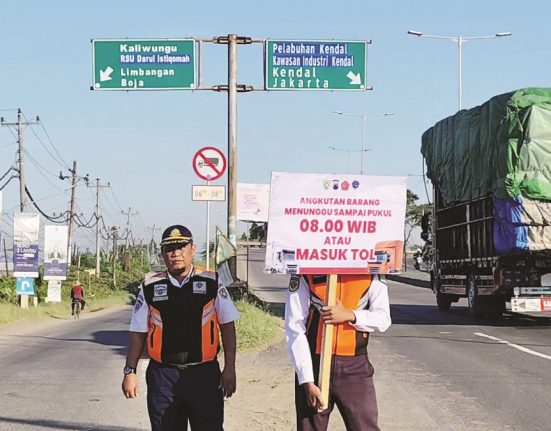 Petugas Dinas Perhubungan Kabupaten Kendal memasang papan pengumuman pembatasan jam operasional truk di jalan masuk pantura Kendal, Senin (5/5/2025). (Arvian Maulana | Mantranews.id)