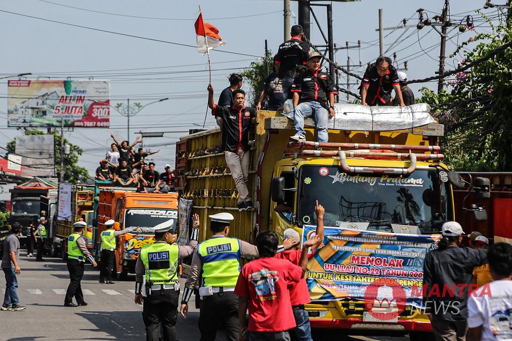 Sejumlah polisi lalu lintas mengarahkan sopir truk yang melakukan aksi solidaritas menolak aturan Over Dimension Over Load (ODOL) di Jalur Pantura Siliwangi Ruas Semarang-Kendal, Semarang, Jawa Tengah, Senin (23/6/2025). (Lingkar Media Group Network)