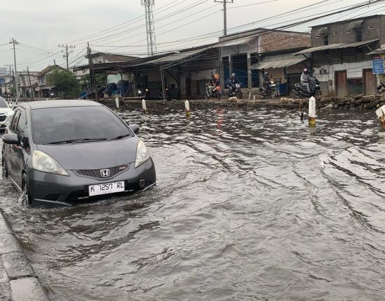 Sebuah mobil melintasi di pantura Semarang-Demak yang digenangi rob. (M. Burhan | Mantranews.id)