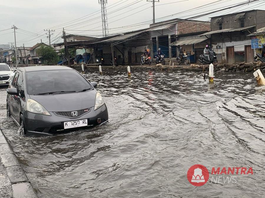 Sebuah mobil melintasi di pantura Semarang-Demak yang digenangi rob. (M. Burhan | Mantranews.id)